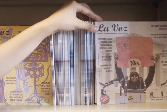 Hand picking one of many La Voz magazines